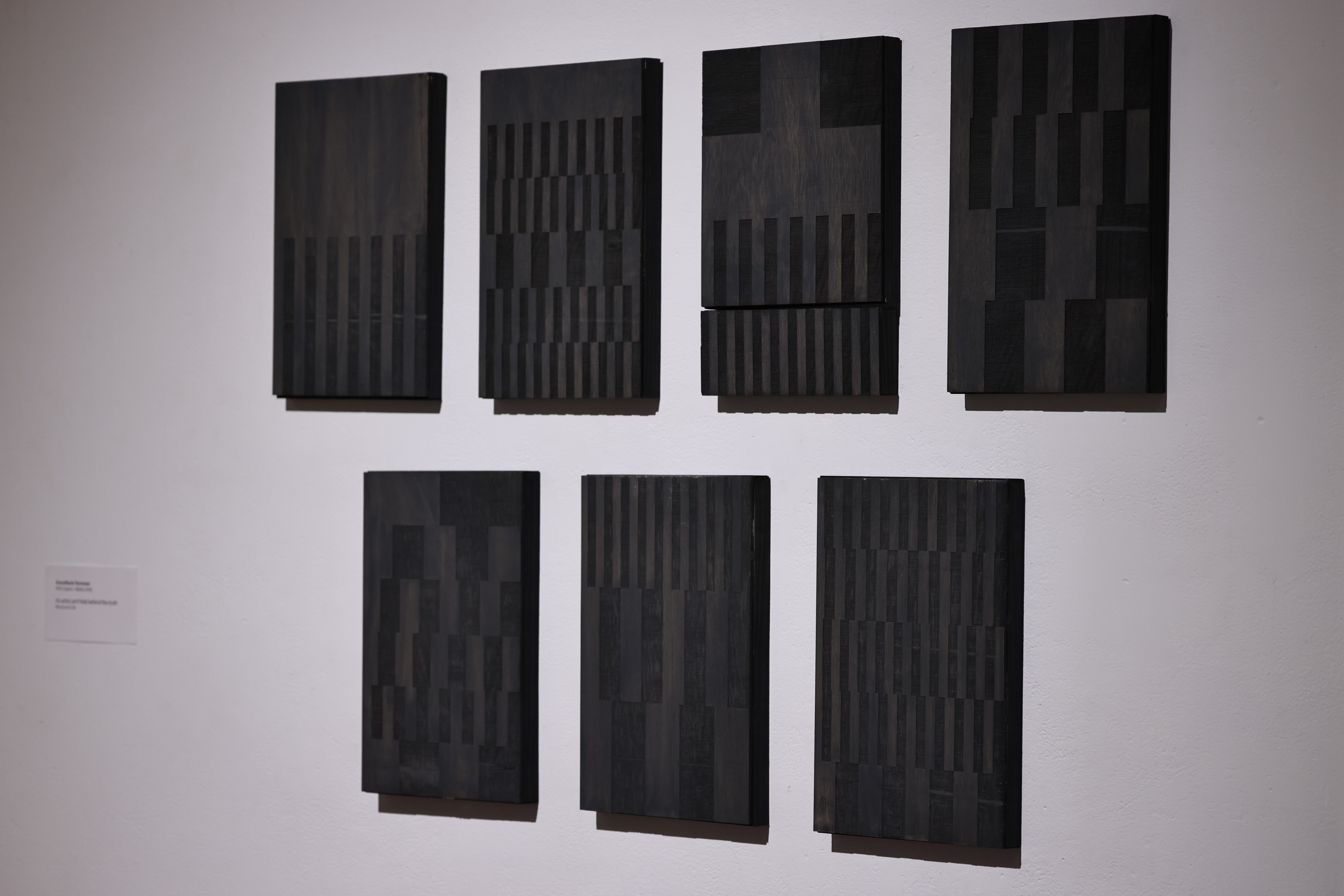 Eight striped wooden panels hanging on a gallery wall